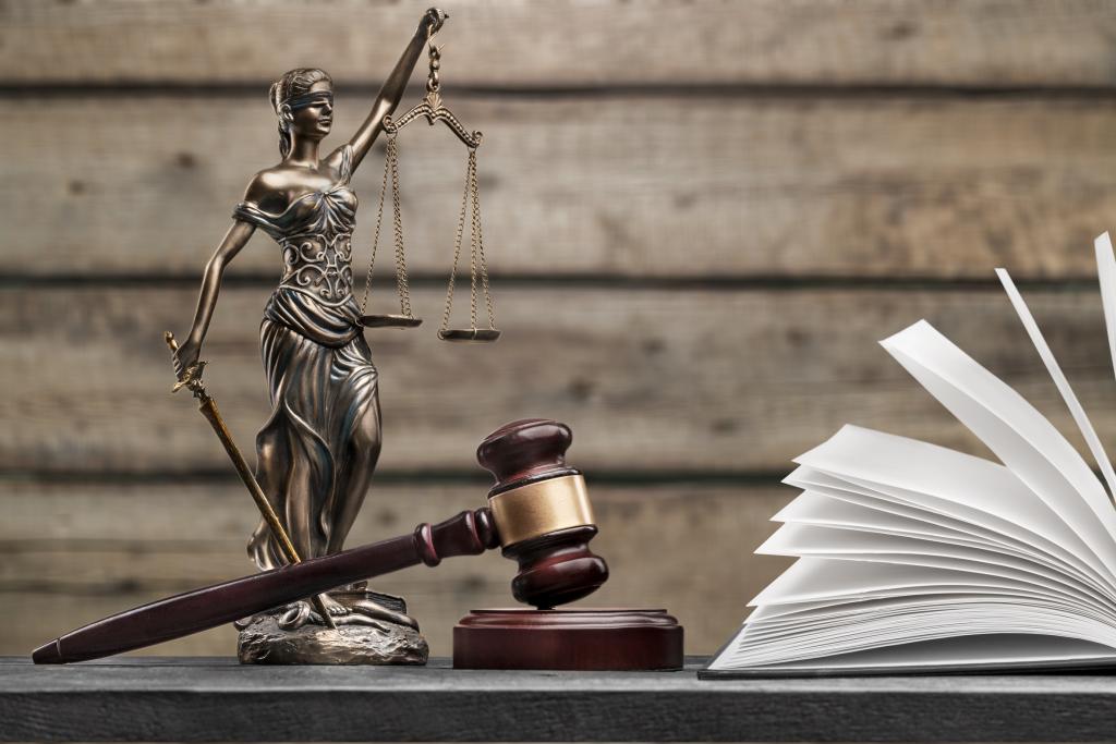 Standbeeld Vrouwe Justitia, hamer en openliggend wetboek